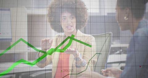 Businesswoman presenting data with rising green charts during collaborative office meeting