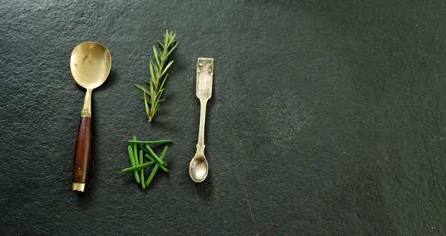 Overhead of two metal spoons with chives and rosemary 4k