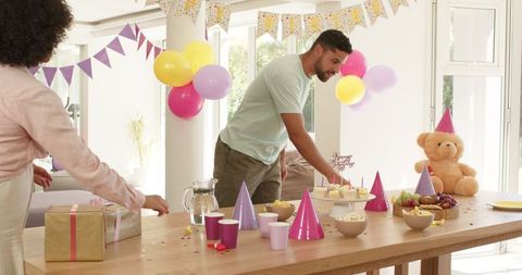 Family setting up vibrant birthday decorations and snacks at home