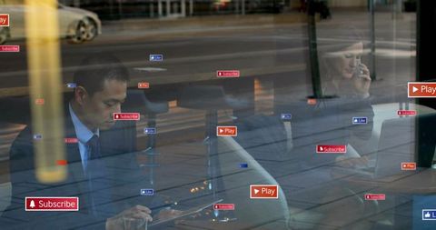 Diverse professionals collaborating with devices in cafe surrounded by social icons and reflections