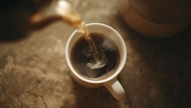 Pouring Hot Coffee into Ceramic Mug on Stone Surface
