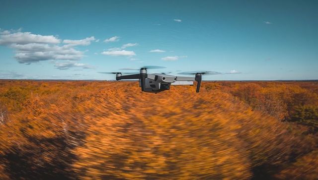 Drone hovering over autumn forest with cinematic motion blur and gimbal camera