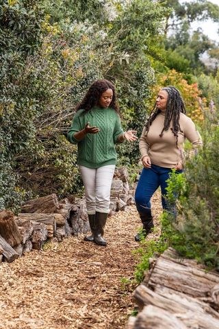 African american women walking and talking on woodchip trail wearing sweaters and boots