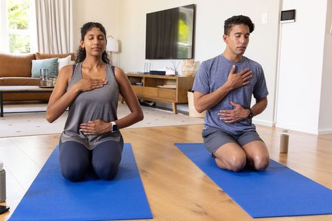African american couple practicing mindful breathing meditation on blue yoga mats at home
