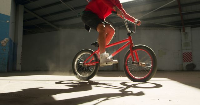 Person is performing BMX stunts indoors, highlighting athleticism and excitement of extreme sports. Perfect for sports magazines, advertisements for bicycle equipment, and promotional materials for extreme sports events.