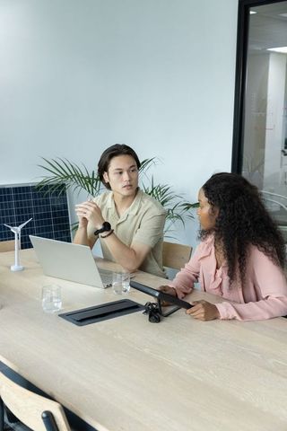 Young diverse colleagues discussing sustainable energy project with laptop and tablet