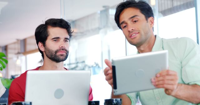 Two Colleagues Discussing Project over Digital Devices in Modern Office - Download Free Stock Images Pikwizard.com