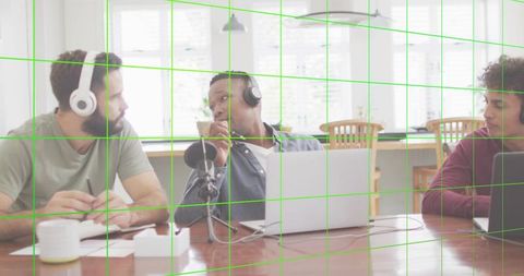 Recording trio wearing headphones leaning into microphone in bright home coworking dining room