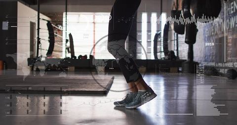 Female balancing on toes in gym with hud fitness data overlay, backlit studio workout