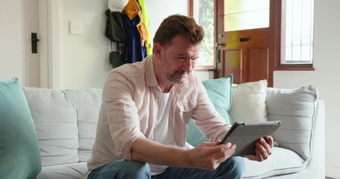 Man in cozy living space engaging with digital tablet