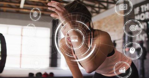 Lean athlete catching breath while training with augmented reality fitness hud in gym