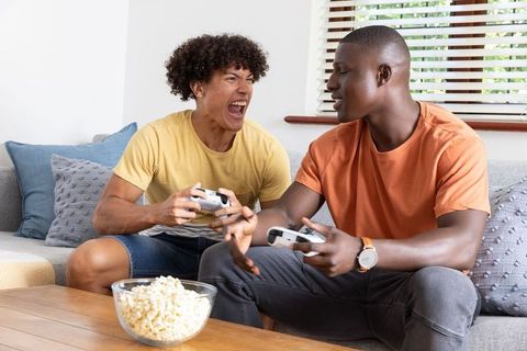 Diverse friends gaming and relaxing with popcorn at home