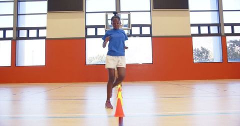 Energetic Girl in Gym Practicing Agility Drills with Colorful Cones