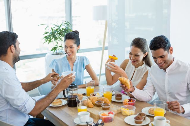 Business colleagues interacting with each other while having breakfast in office cafeteria
