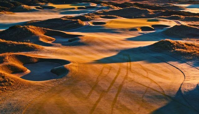 Sunrise sculpted links golf course revealing windblown bunkers, fairways and tracks