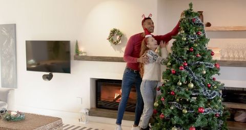 Couple Joyfully Decorating Christmas Tree in Cozy Living Room