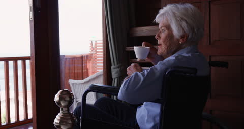 Senior Woman Relaxing on Wheelchair and Enjoying Coffee at Home