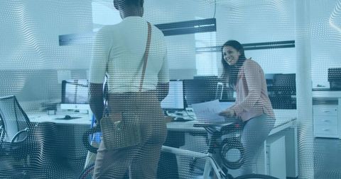 Smiling professional leaning on desk holding documents in coworking office with bicycle