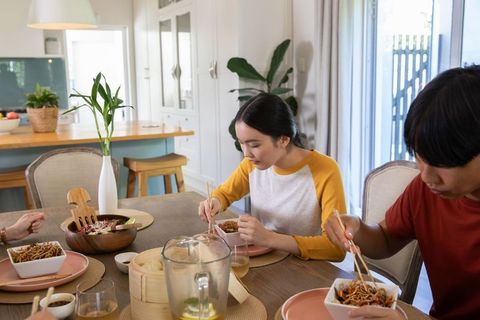 Asian couple enjoying homemade noodles in modern dining room