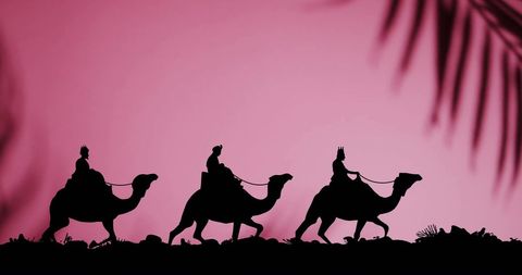 Silhouette of wise men riding camels at sunset