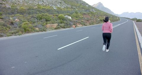 Woman Jogging on Mountain Road with Scenic Backdrop