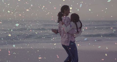 Mother carrying daughter on beach at dusk with confetti overlay, joyful family bonding