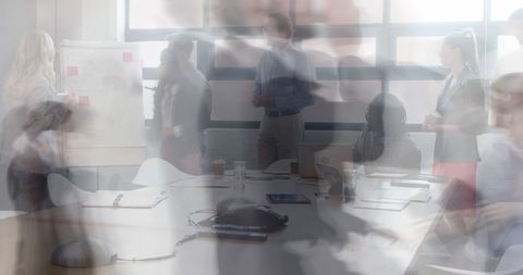 Blurred business team collaborating and brainstorming around conference table in office
