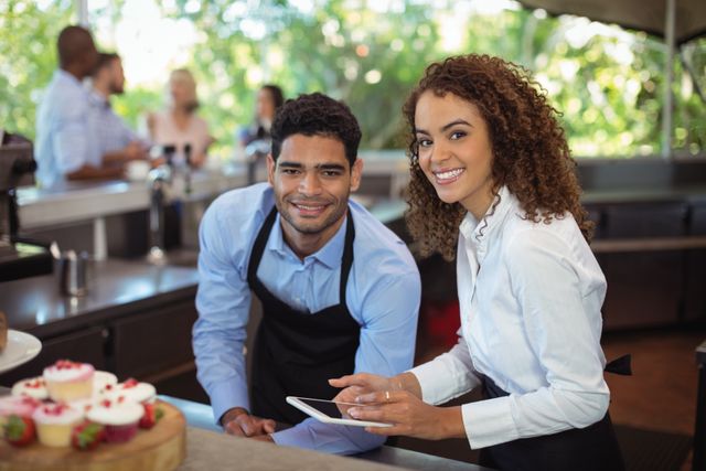 Male waiter and female waitress with digital tablet at outdoor restaurant