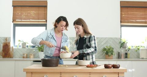African women serving homemade pasta on wooden kitchen island in bright modern kitchen