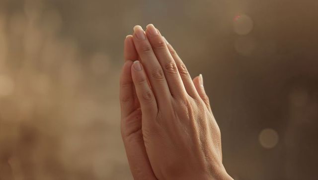Hands in Prayer Gesture with Warm Bokeh Background