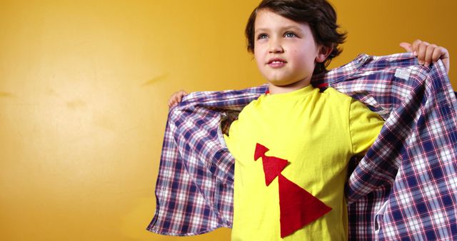 Confident Boy Unveiling Superhero Shirt on Yellow Background - Download Free Stock Images Pikwizard.com