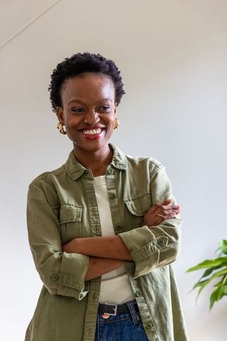 Smiling african american woman standing with arms crossed wearing casual olive shirt and denim