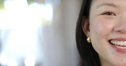 Closeup portrait of asian woman smiling with gold earring, soft natural light and bokeh