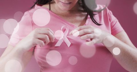 Woman Pinning Pink Ribbon for Breast Cancer Awareness