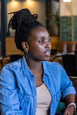African woman speaking at cafe wearing denim shirt and smartwatch, casual conversation