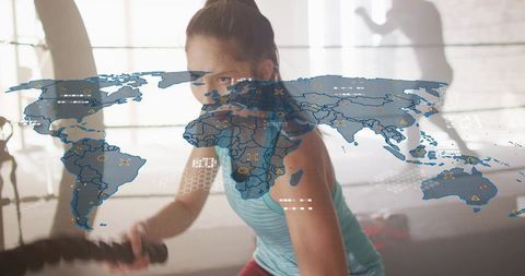 Female athlete swinging battle ropes with futuristic world map overlay for fitness tech