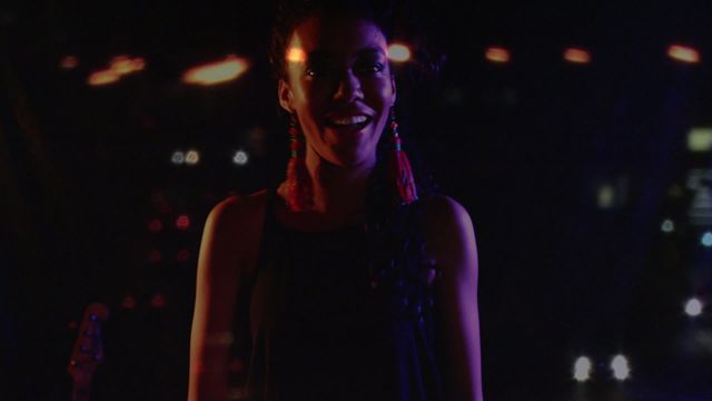 A vibrant image capturing a joyous female singer immersed in the bright allure of night-time city lights. Ideal for showcasing themes of nightlife, live entertainment, or musical performances. This image can be effectively used in concert promotions, music festival advertisements, or city lifestyle blogs.