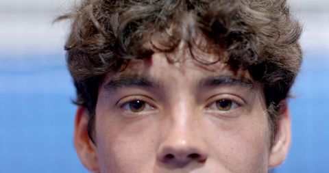 Curly hair male model staring intently against blue backdrop
