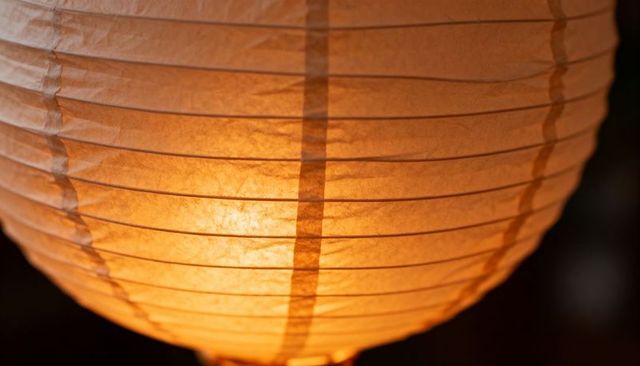 Glowing Spherical Paper Lantern Hanging Closeup with Warm Amber Light and Ribbed Texture
