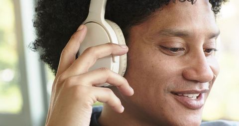African american man listening with beige over-ear headphones close-up natural light