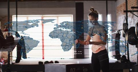 Female athlete adjusting wrist wrap in industrial boxing gym with futuristic ar map overlay
