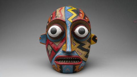 Colorful geometric tribal wooden mask with exaggerated eyes and carved teeth