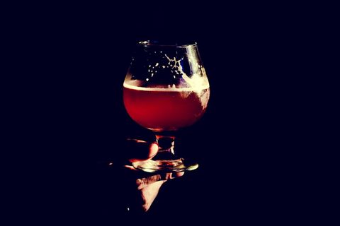 Hand Holding a Craft Beer Glass Against Dark Background