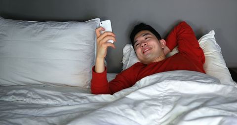 Relaxed Man Using Smartphone in Cozy Bedtime Setting