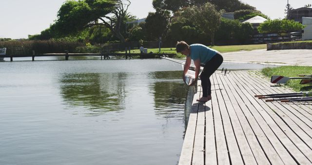 Person Preparing Boat by Lakeside Dock on Sunny Day - Download Free Stock Images Pikwizard.com