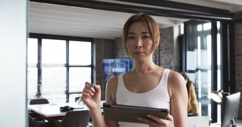Confident businesswoman holding tablet standing in modern office