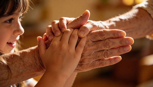 Grandchild holding grandparent hands close-up showing warm multigenerational bond