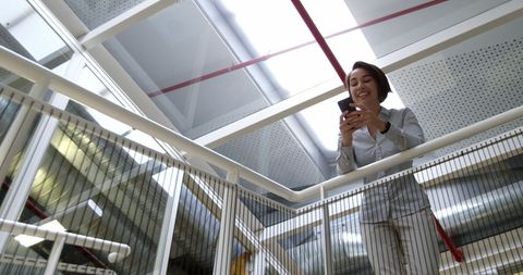 Businesswoman Texting on Smartphone in Modern Office Atrium