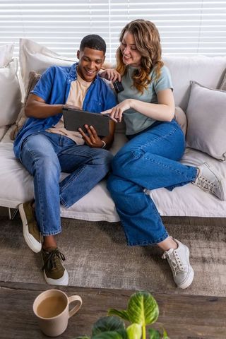 Young couple relaxing on couch using tablet for online shopping and streaming