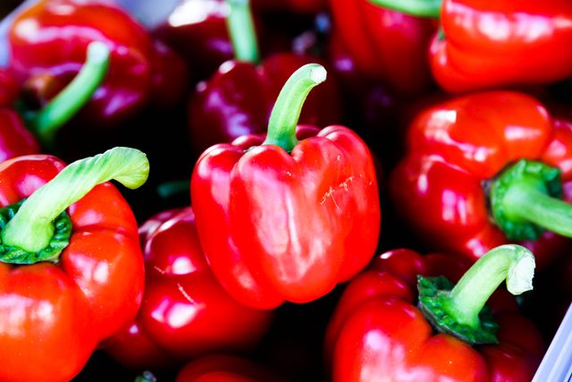 This shows multiple fresh red bell peppers laid out. Use this in contexts around healthy eating, fresh produce, nutrition, cooking, or farmers markets. Ideal for blogs, advertisements, cooking websites, and educational content centered around food and health.